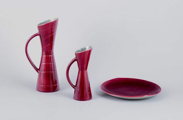 Carl Harry Stålhane (1920-1990) for Rörstrand. Two pitchers and a plate in ceramic. Burgundy-colored glaze.