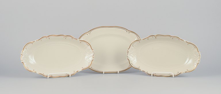KPM, Polen. Tre aflange fade i porcelæn.Cremefarvet, dekoration med guldkant.