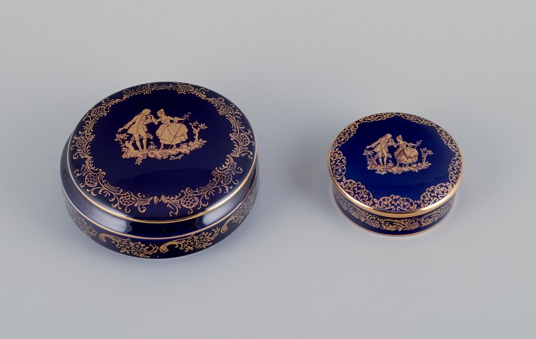 Limoges, France. Two round covered jars in porcelain decorated with 22-karat gold leaf and beautiful royal blue glaze. Scène galante.