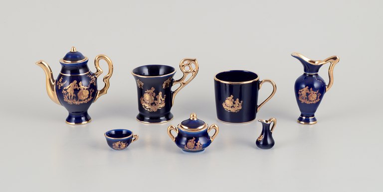 Limoges, France. Seven pieces of miniature porcelain, decorated with 22-karat gold leaf and a beautiful royal blue glaze. Scène galante.