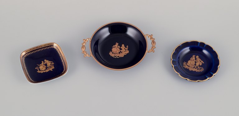 Limoges, Frankrig.  Tre små skåle i porcelæn dekoreret i 22-karat bladguld. Smuk kongeblå glasur. Scène galante.