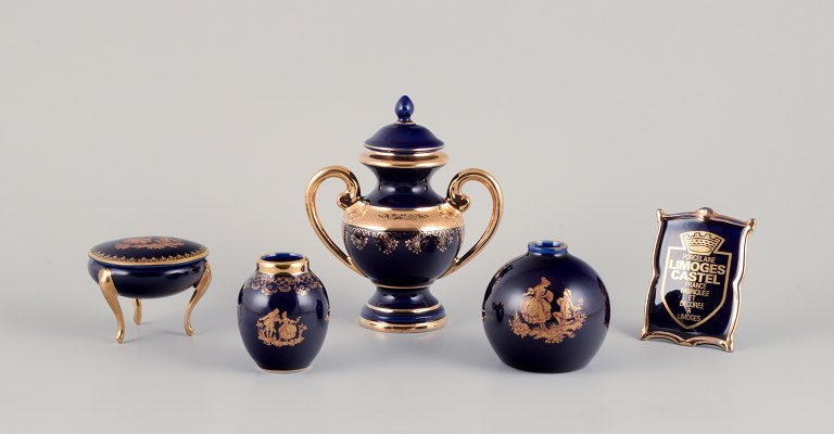 Limoges, Frankrig. Fem dele porcelæn bestående af pokal, to vaser, lågkrukke på tre fødder samt samt skilt. Dekoreret i 22-karat bladguld.Smuk kongeblå glasur.
