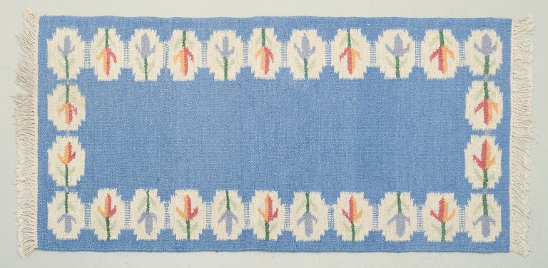 Swedish handwoven carpet in pure wool. Rölakan technique.Designed with flowers on a blue background.
