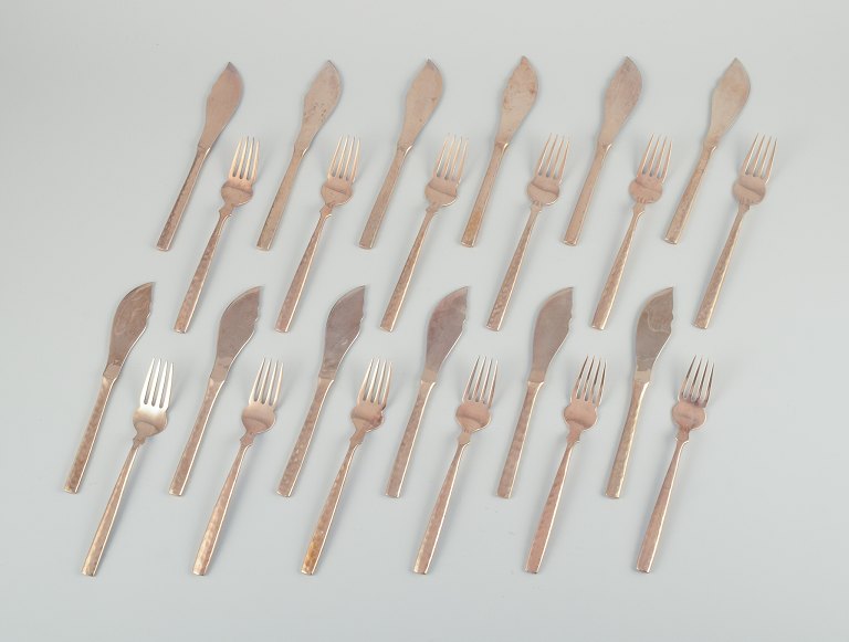 Skandinavisk designer. Komplet tolvpersoners fiskeservice bestående af tolv fiskeknive og tolv fiskegafler i hammerslået messing. Håndlavet i høj kvalitet.