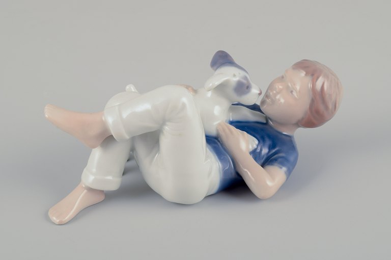 Royal Copenhagen.Porcelænsfigur af dreng med hundehvalp.