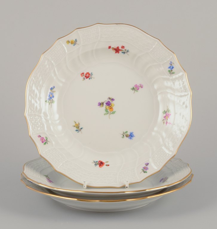 Meissen, Germany. Three porcelain luncheon plates.Hand-painted with polychrome floral motifs.
