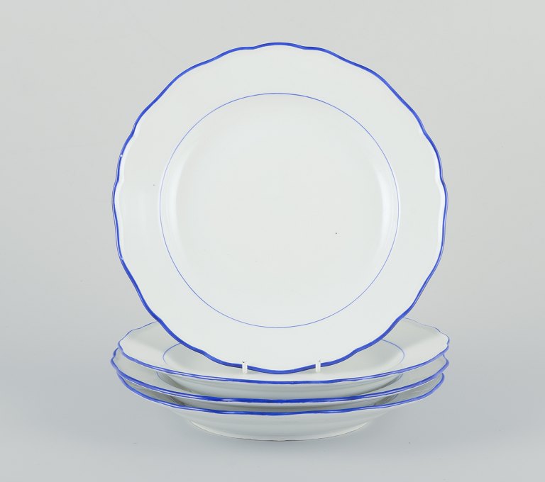 Meissen, Germany. A set of four dinner plates.White porcelain with blue rim.