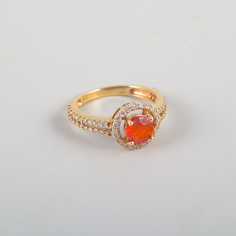14 karat gold ring adorned with an orange opal and numerous brilliant-cut diamonds.